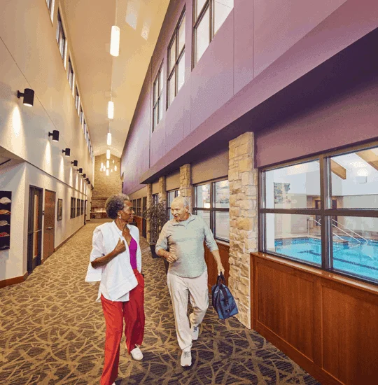 Senior couple walking in hallway next to the pool area