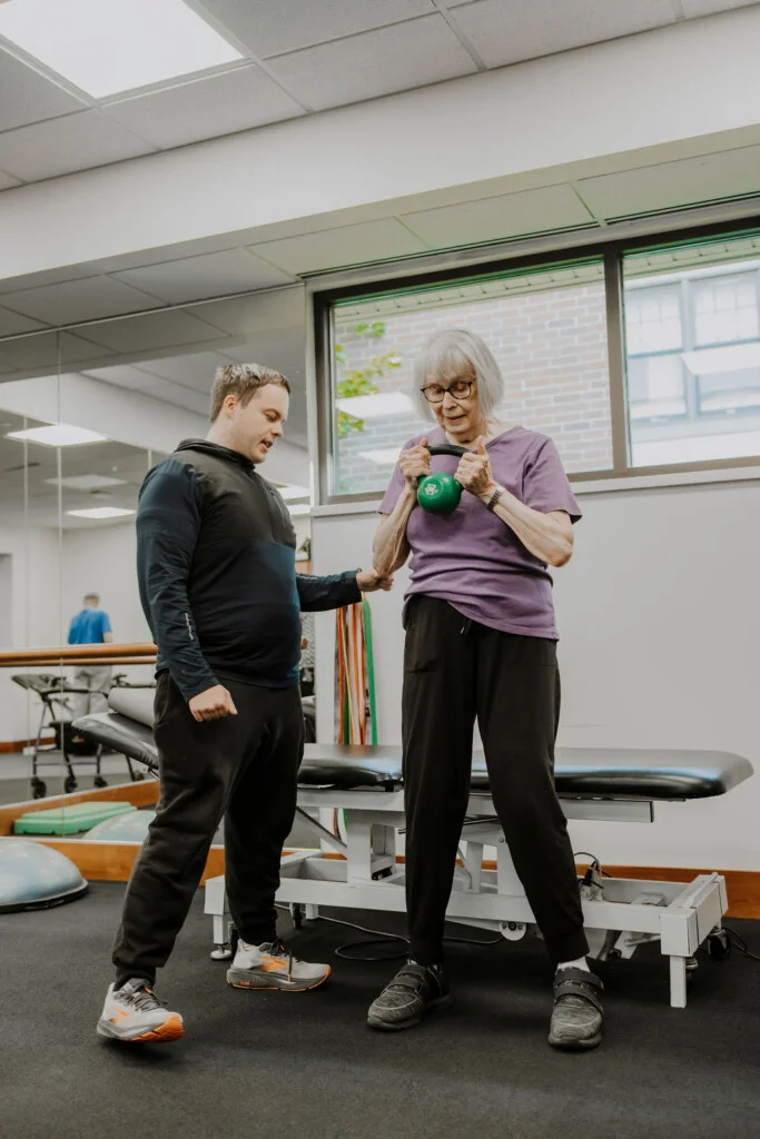 Fitness trainer guiding a resident through a kettlebell exercise at Friendship Village of Bloomington