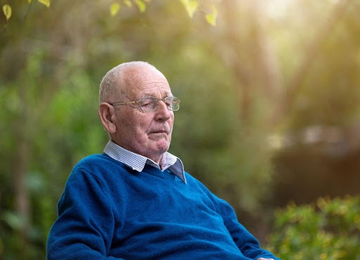 elderly man sitting outside his assisted living facility
