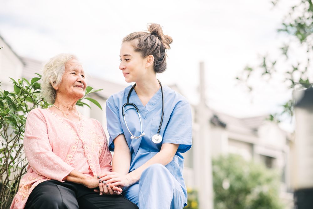 Senior woman holding hands with a nurse outside