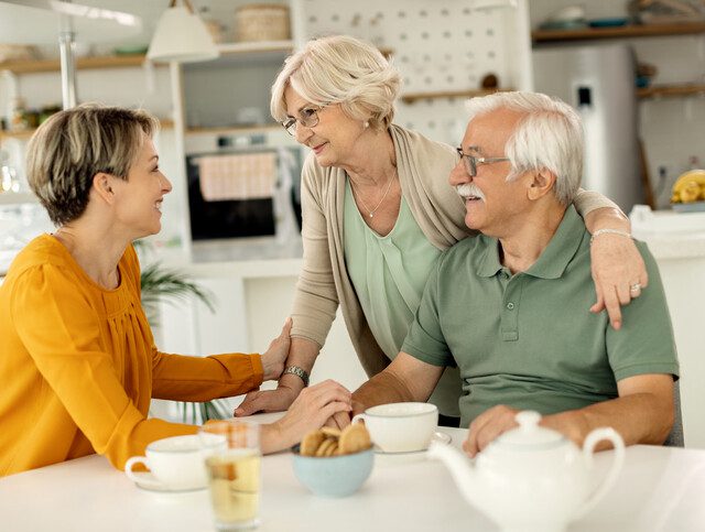 Happy woman visiting her senior parents and communicating with them at home.