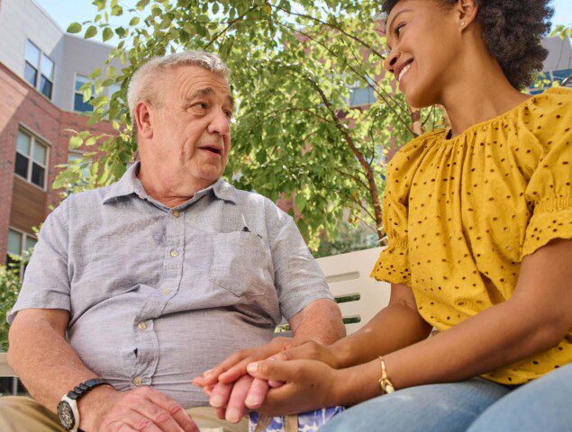 young woman holding hand on older man and smiling