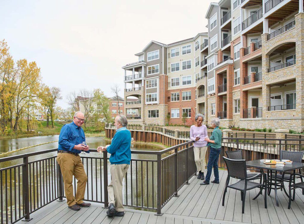 2 men talking and 2 women walking outside near lake