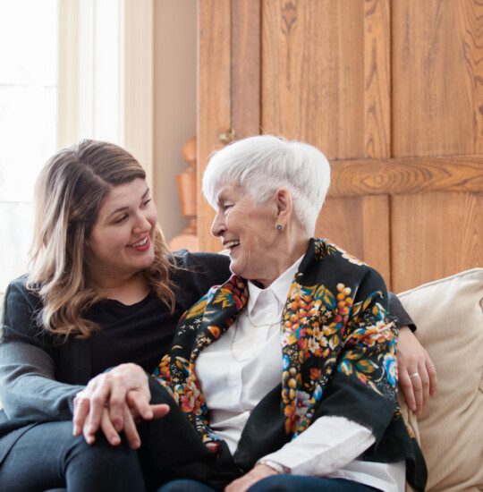 older woman and younger woman on sofa looking at each othwr