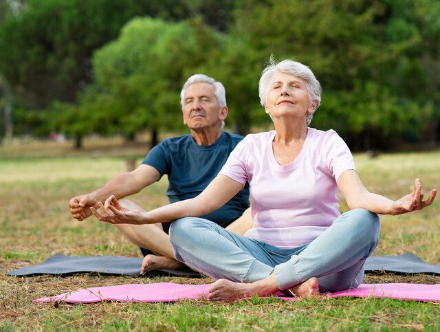A senior woman and a senior man practicing yoga