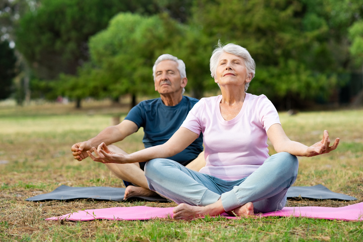 A senior woman and a senior man practicing yoga