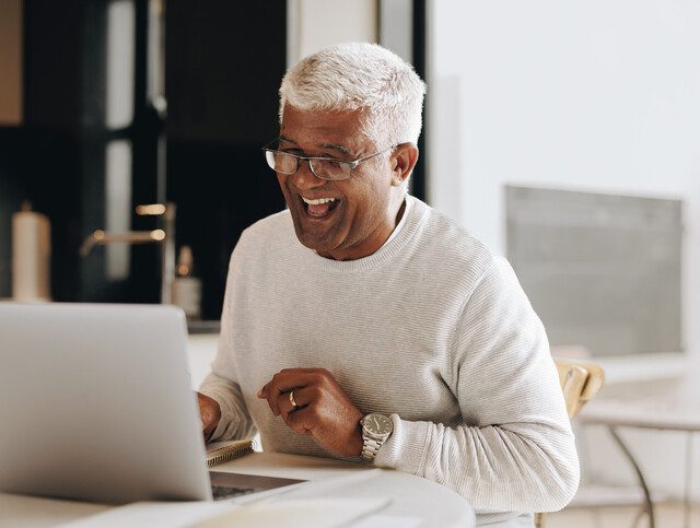 Senior man sitting with a laptop computer in front of him