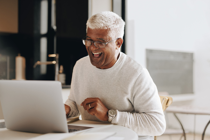 Senior man sitting with a laptop computer in front of him