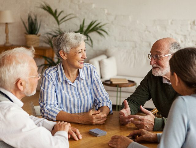 Older adults engaged in conversation around a table.