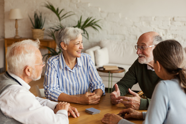 Older adults engaged in conversation around a table.