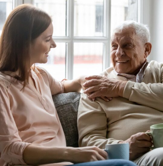 adult woman talks with her happy older father