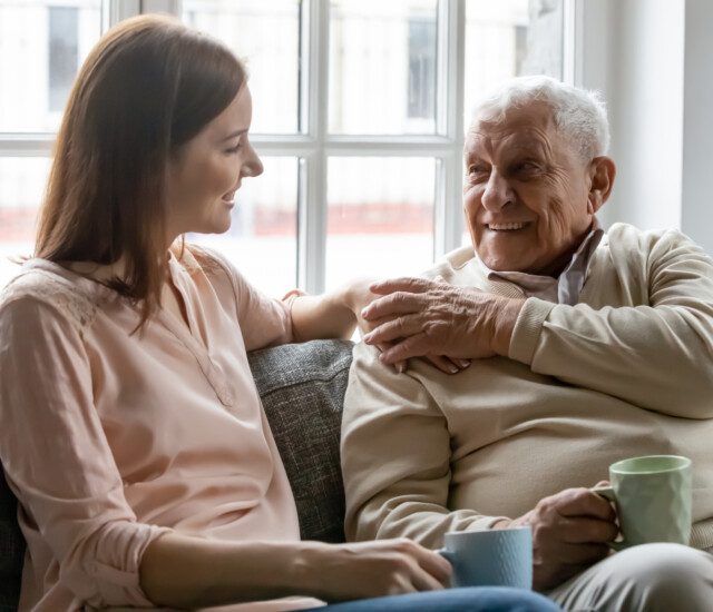 adult woman talks with her happy older father